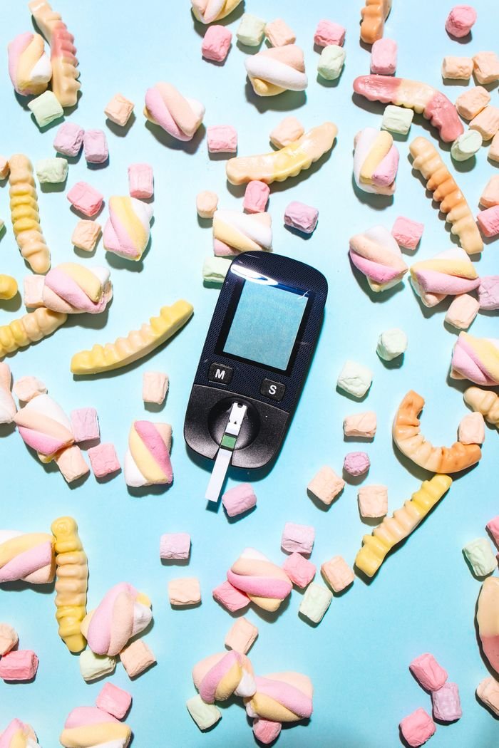 Glucometer surrounded by colorful candies, symbolizing diabetes health concerns.